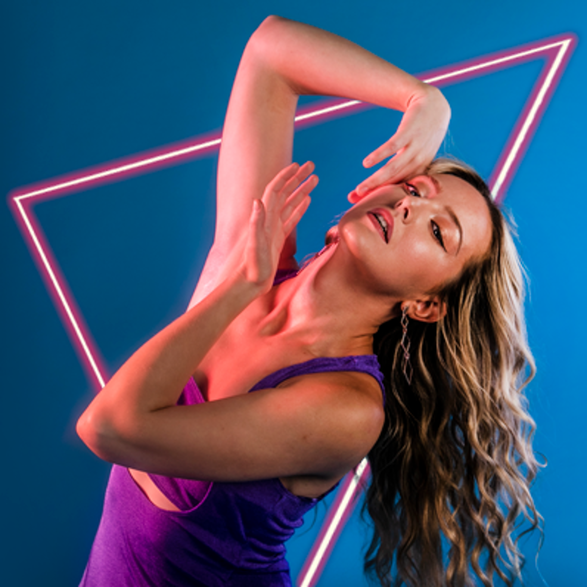 contemporary dancer flicking hair to the right side of the image with hands held either side of her face on bright blue studio backdrop. white blonde females wearing a long purple dress. 