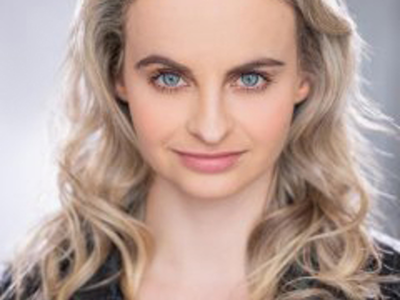 Headshot of Anita Mannings. white female with long curly blonde hair looking at the camera