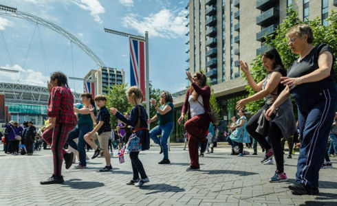 children and adults dancing in the street with large union jack flags 