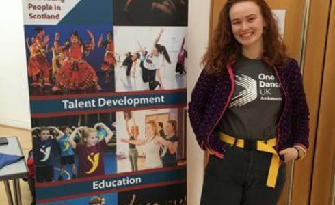 White female one dance uk dance ambassador standing in front of a Y Dance pull up banner