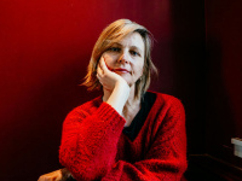 Headshot of Mary Davies. White blonde female with wearing red jumper