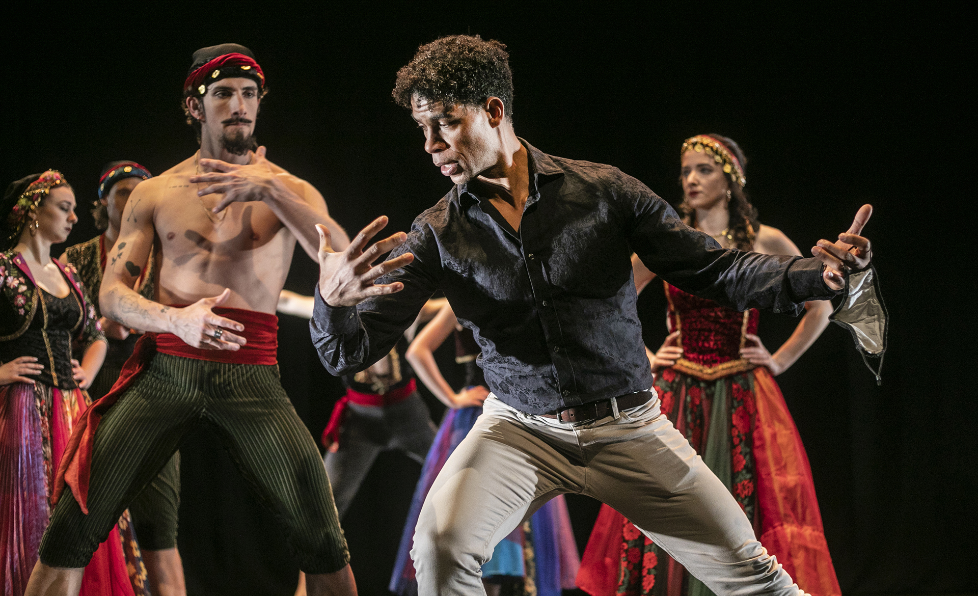 Male cuban dancer Carlos Acosta leaning to the left pretending to hold someone showing male dancer how to perform the move. All in colourful traditional cuban costumes Male cuban dancer Carlos Acosta leaning to the left pretending to hold someone showing male dancer how to perform the move. All in colourful traditional cuban costumes