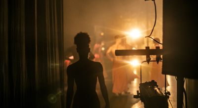backstage image of orange lights on stage and silhouette of dancer about to walk on 