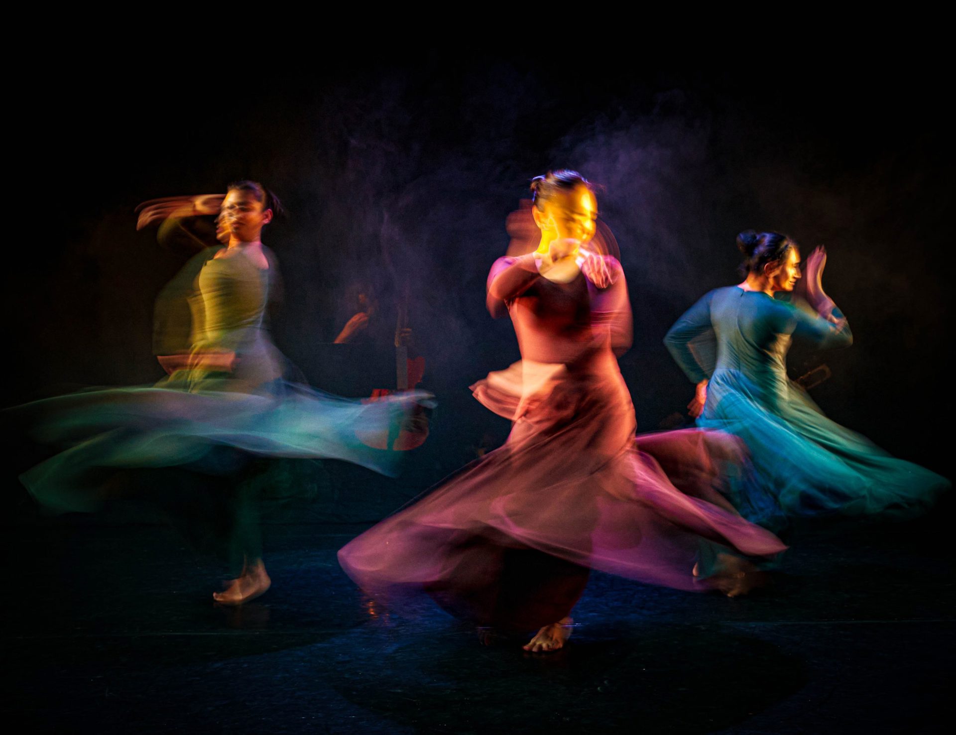 Three female south asian dancers spinning in dresses with motion blur