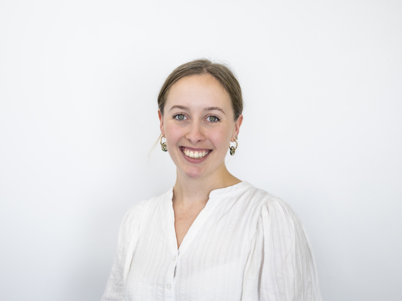 Headshot of Jess Lowe. white female with blonde hair tied back smiling at the camera with a white shirt