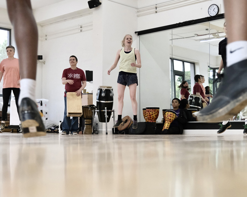 class of young people all wearing tap shoes, jumping feet in the forground jumping teacher in the background 