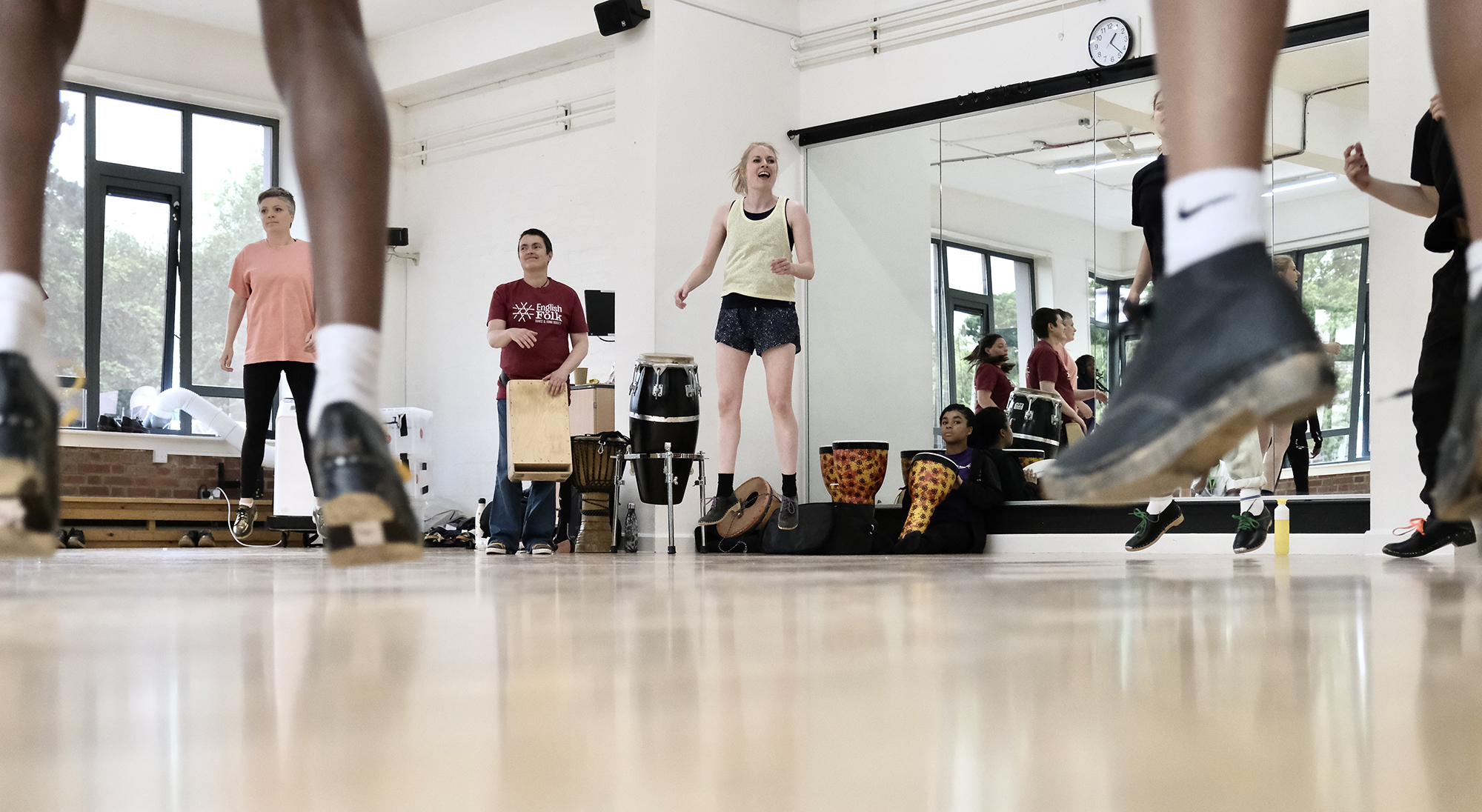 class of young people all wearing tap shoes, jumping feet in the forground jumping teacher in the background 