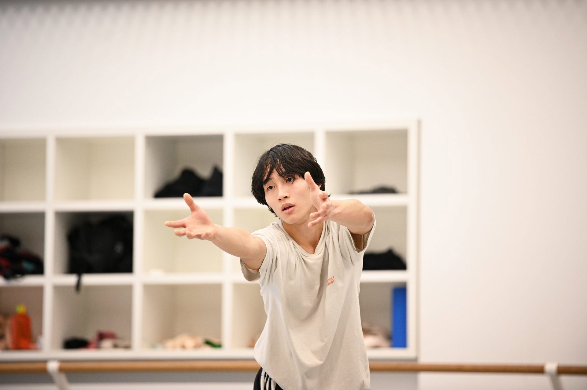 global majority male dancer in a white studio reaching forward global majority male dancer in a white studio reaching forward
