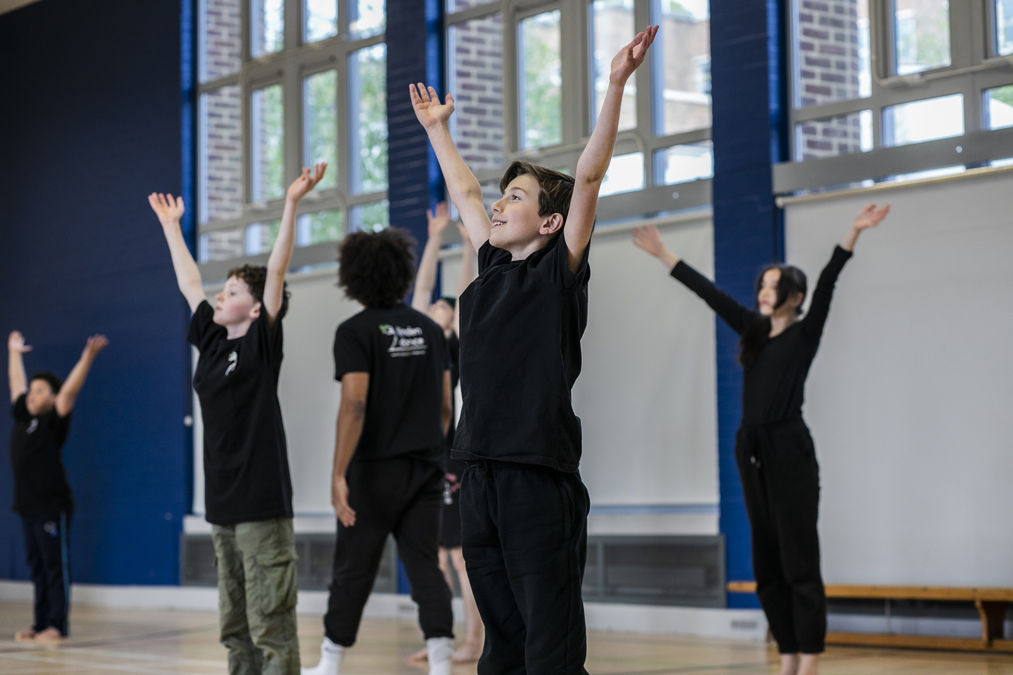 primary school boys and girls all reaching up to the sky in a sports hall primary school boys and girls all reaching up to the sky in a sports hall