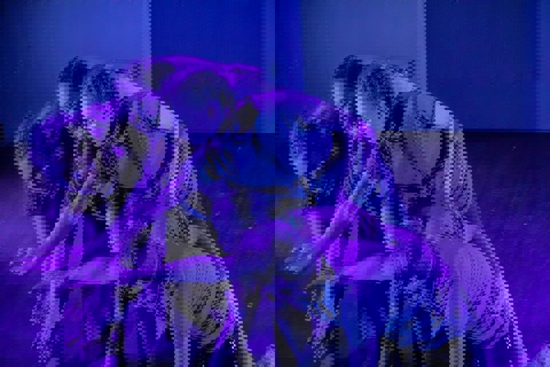 six young dancers all huddled together reaching for the same spot in the bottom left on the screen with blue lighting six young dancers all huddled together reaching for the same spot in the bottom left on the screen with blue lighting