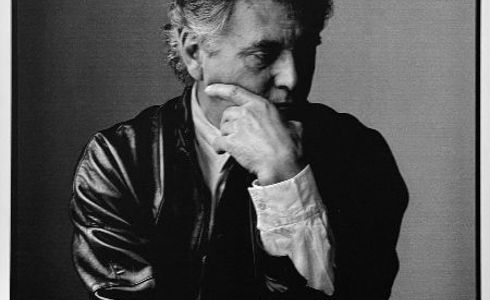 black and white headshot of a male holding his face and looking down