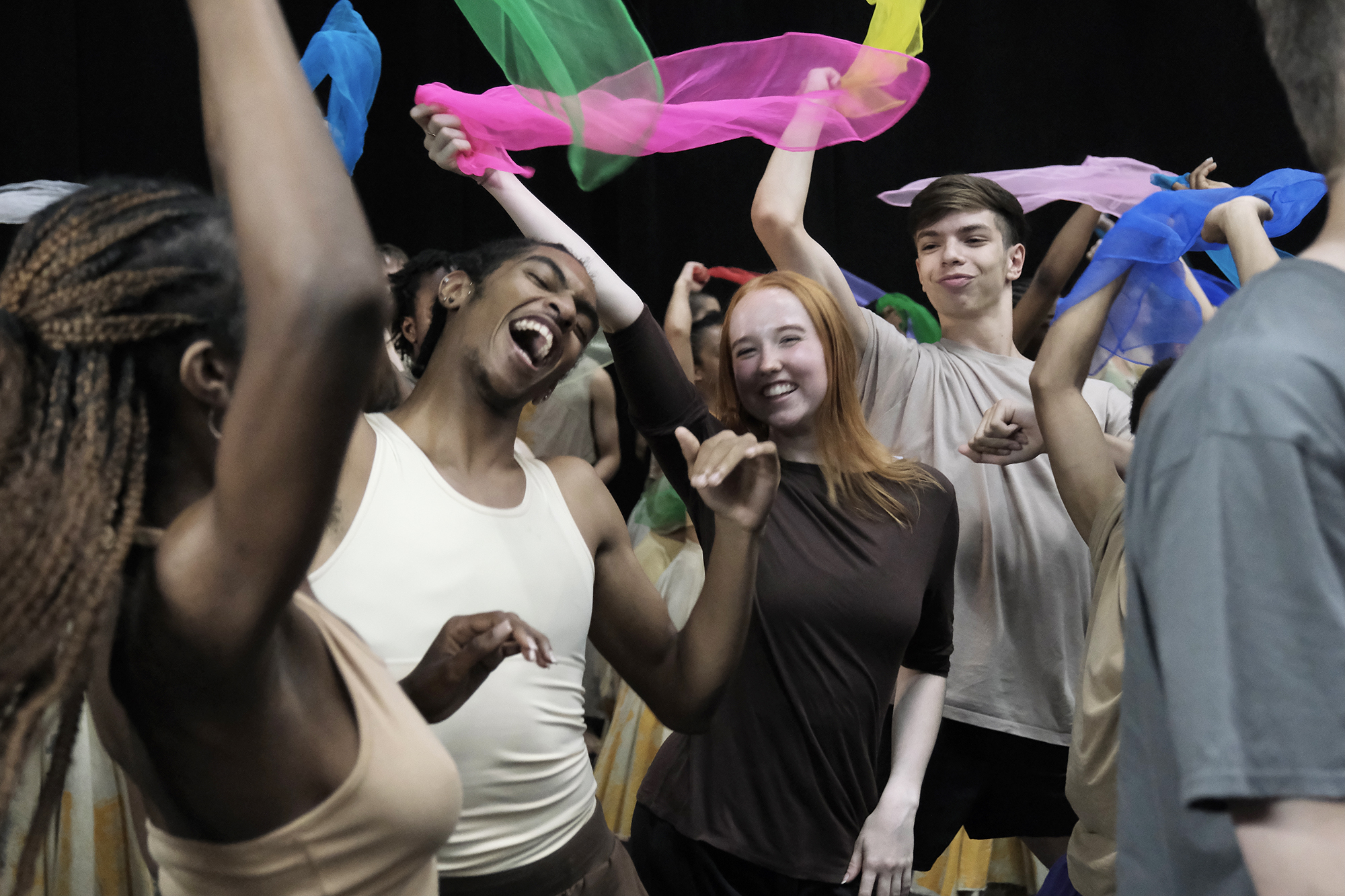 young people mixed genders and races dancing together with big smiling faced waving brightly colour scarfs.  young people mixed genders and races dancing together with big smiling faced waving brightly colour scarfs.