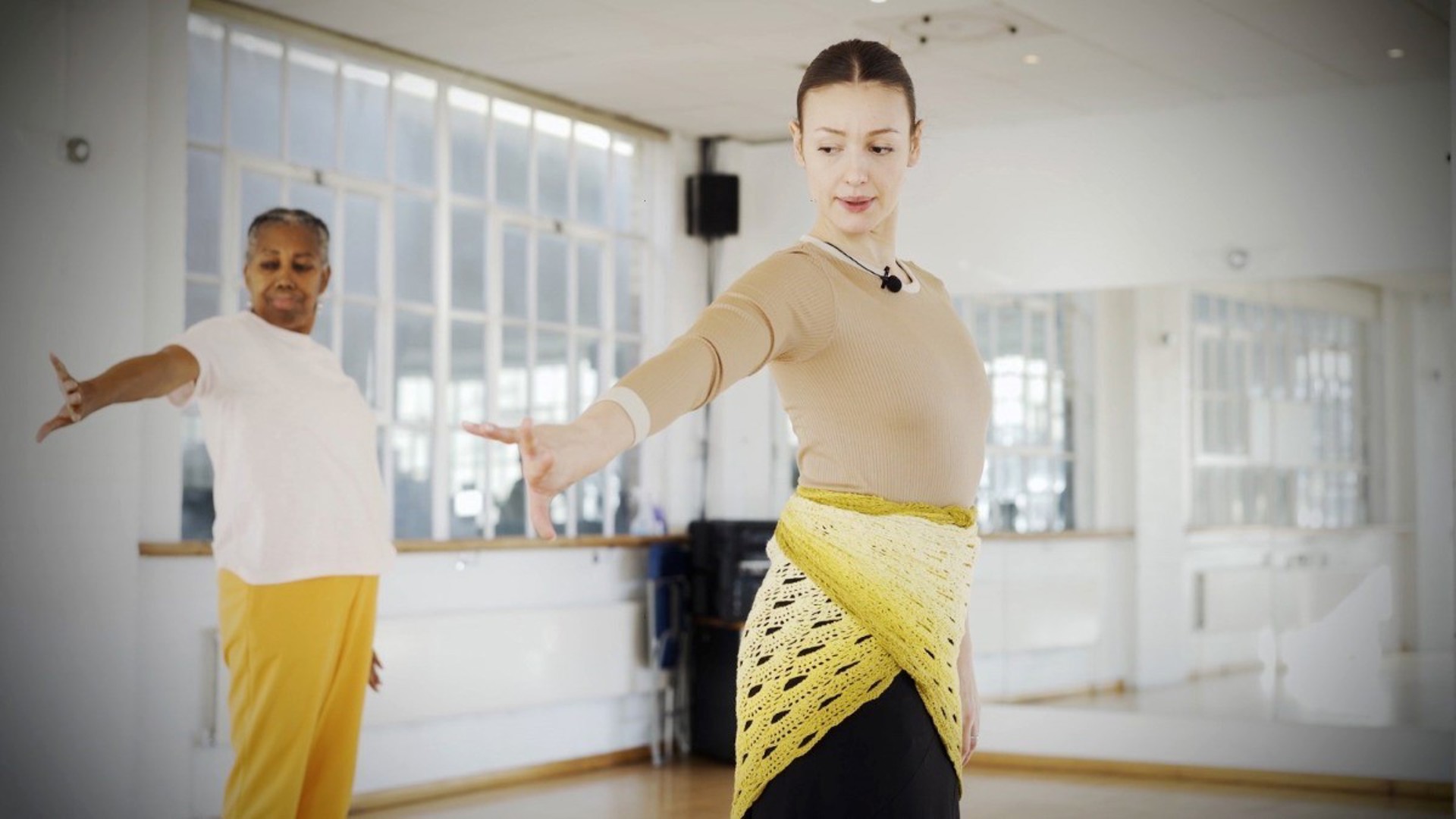 two female dancers long left hand out looking down in a mirrored dance studio