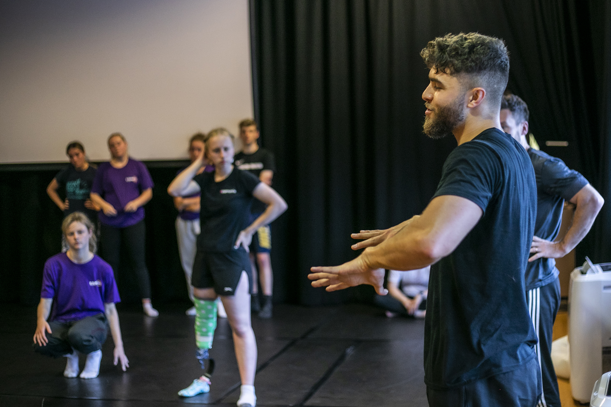 white male dancer guestering to dance students in a blacked out dance studio white male dancer guestering to dance students in a blacked out dance studio