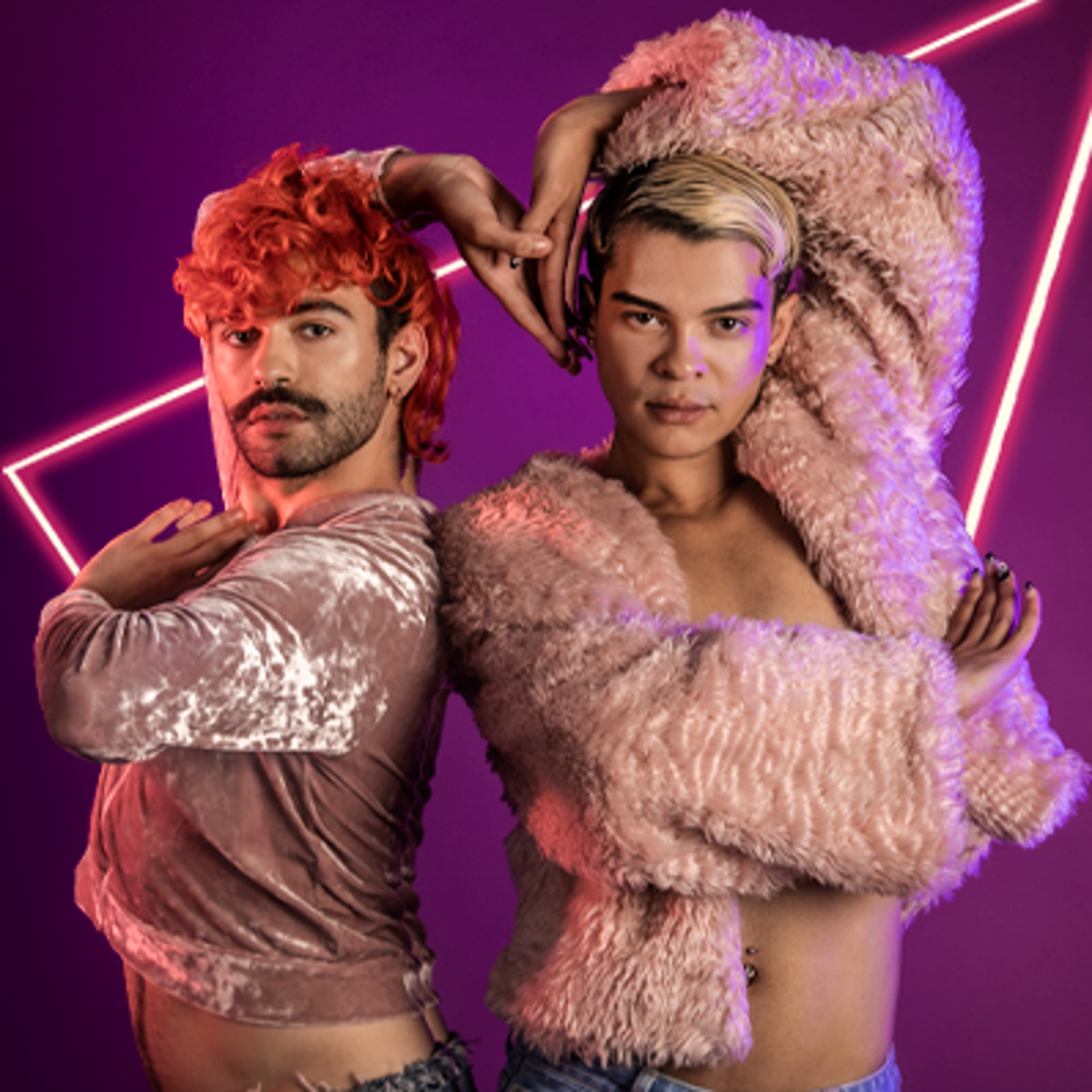 Two global majority LGBTQ+ male voguing dancers. Wearing pink tops in a purple studio. Standing next to eachother with outside hands leaning over their heads and joining together in the middle over eachother. 